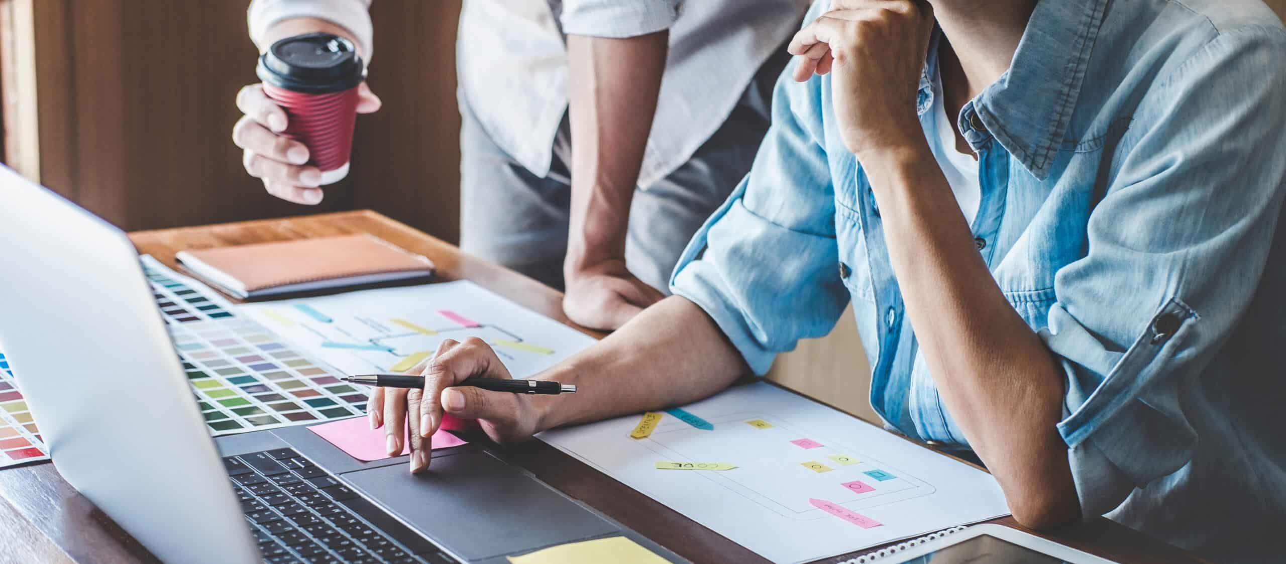 Zwei Personen vor einem Laptop und Arbeitspapieren